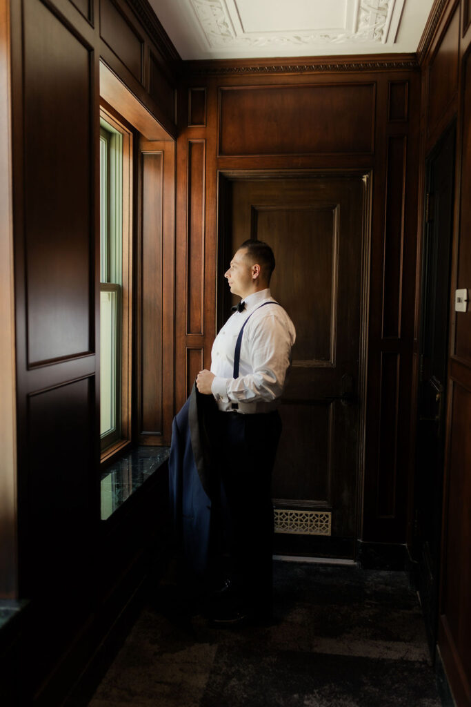 groom getting ready in front of window at bottleworks hotel in indianapolis