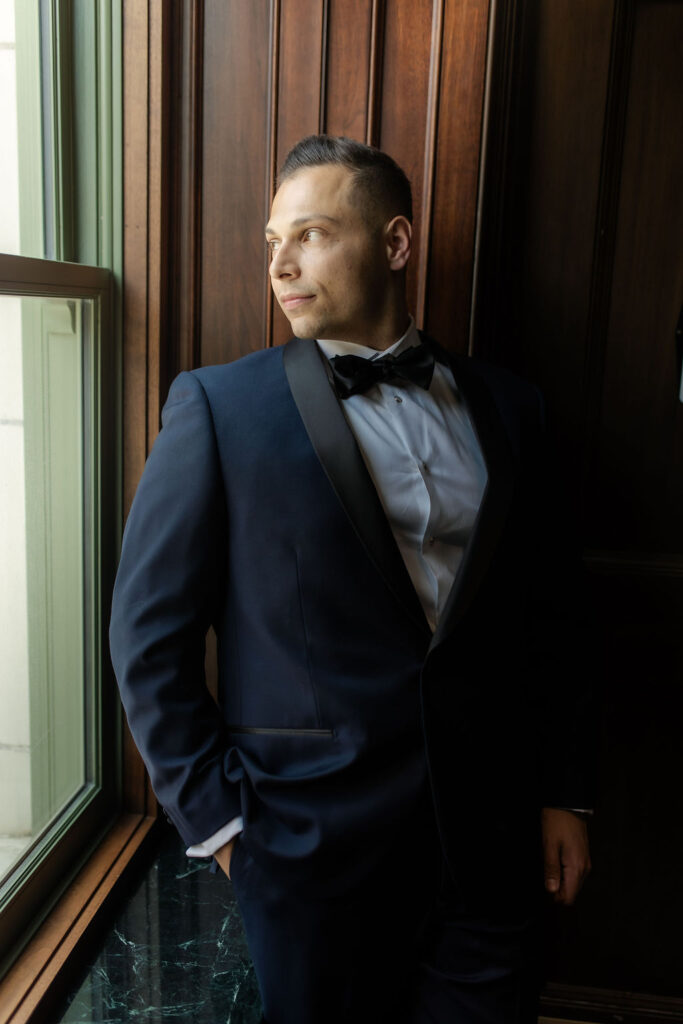 groom standing in front of window at bottleworks hotel