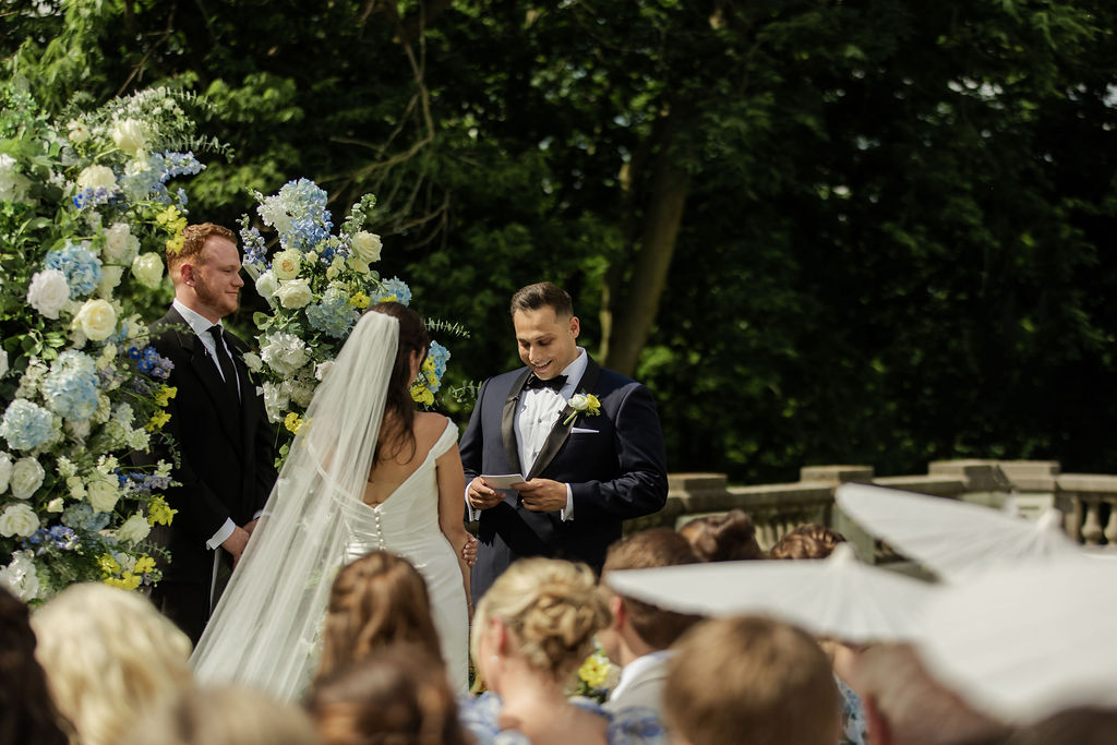 bride reading vows to his groom during the ceremony at newfields, grooms reaction