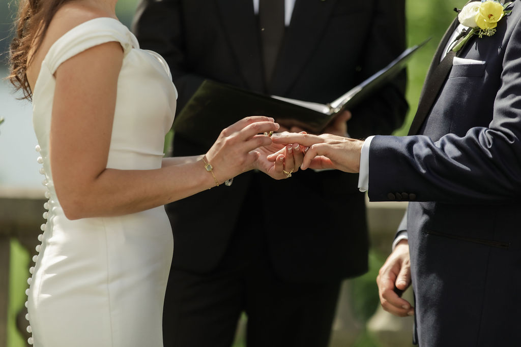 close up shot by Natalie Marie Photo of bride and groom putting on their rings during the ceremony vows